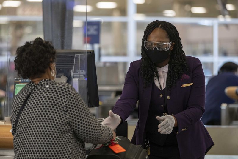 11/23/2020 �  Atlanta, Georgia �A Delta Air Lines employee handles a passengers luggage while wearing goggle, gloves and a face mask in the Domestic Terminal at Hartsfield-Jackson Atlanta International Airport in Atlanta , Monday, November 23, 2020.  (Alyssa Pointer / Alyssa.Pointer@ajc.com)