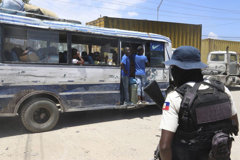 A bus passes by a police officer on patrol near the airport in Port-au-Prince, Haiti, Friday, May 24, 2024. (AP Photo/Odelyn Joseph)