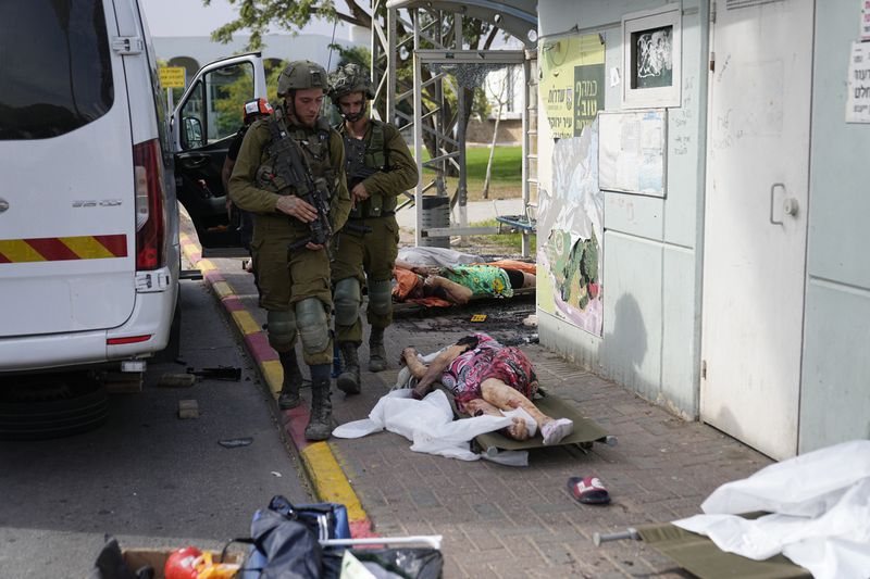 Israeli soldiers walk by civilians killed by Palestinian militants in Sderot, Israel, on Saturday, Oct. 7, 2023. (AP Photo/Ohad Zwigenberg)