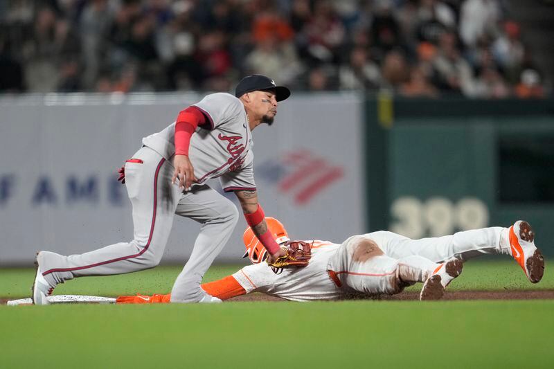 San Francisco Giants' Matt Chapman, bottom, is tagged out by Atlanta Braves shortstop Orlando Arcia while trying to steal second base during the sixth inning of a baseball game in San Francisco, Tuesday, Aug. 13, 2024. (AP Photo/Jeff Chiu)