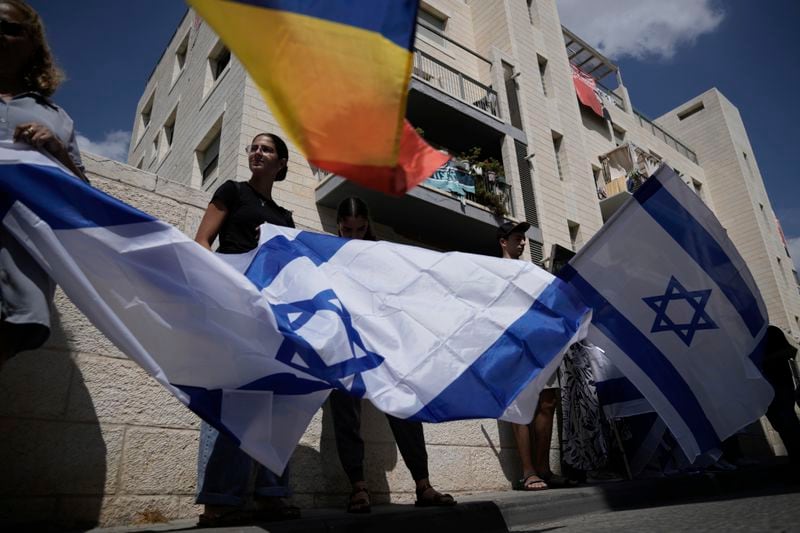 Mourners wave Israeli flags as they accompany the family of Israeli-American hostage Hersh Goldberg-Polin, who was killed in Hamas captivity in the Gaza Strip, on their way to his funeral in Jerusalem, Monday, Sept. 2, 2024. Israel said Sunday it recovered the bodies of six hostages, including Goldberg-Polin's. (AP Photo/Leo Correa)