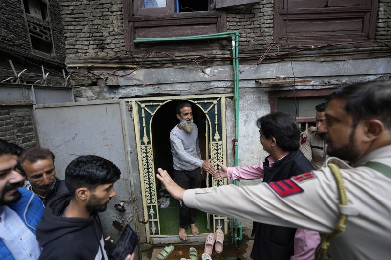 Ashok Bhat, right, a candidate of the Bharatiya Janata Party (BJP) shakes hand with a voter while campaigning door-to-door ahead of the Jammu and Kashmir state assembly elections in Srinagar, Indian controlled Kashmir, Thursday, Aug. 29, 2024.(AP Photo/Mukhtar Khan)