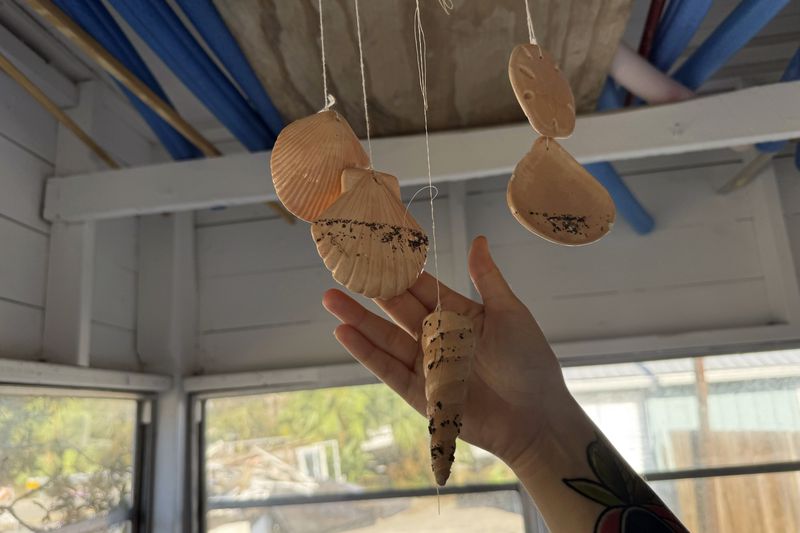 Maddie Kelley shows the high-water line left behind by Hurricane Helene on a seashell windchime at her family's home in Steinhatchee, Fla., Saturday, Sept. 28, 2024. (AP Photo/Kate Payne)