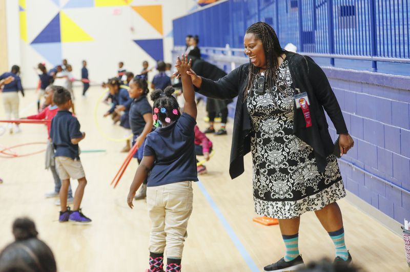 Harper-Archer Elementary School Principal Dione Simon Taylor high fives a student during the monthly "Gym Jam", an event to reward students who have earned enough points to attend.    Bob Andres / robert.andres@ajc.com