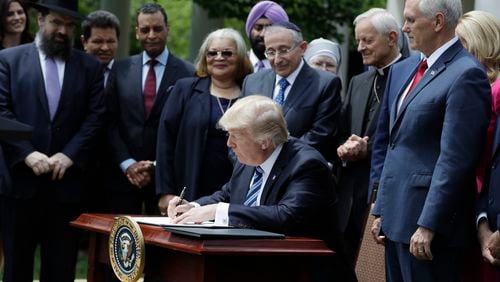 President Donald Trump signs an executive order in the Rose Garden of the of the White House in Washington on Thursday, asking the IRS to use "maximum enforcement discretion" over the regulation, known as Johnson Amendment, which applies to churches and nonprofits AP/Evan Vucci