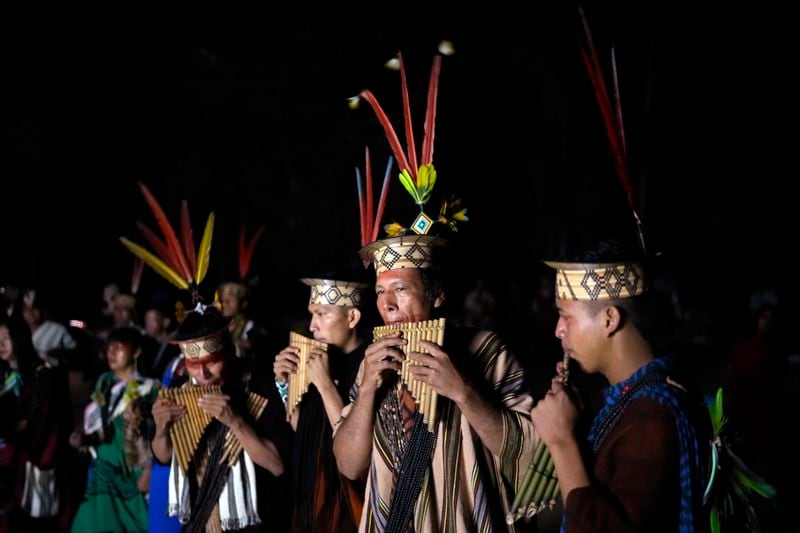 Ashaninka Indigenous people from Brazil and Peru perform at dawn during the annual celebration recognizing the Ashaninka territory in the Apiwtxa village, Acre state, Brazil, Monday, June 24, 2024. At center is Moises Piyako. (AP Photo/Jorge Saenz)