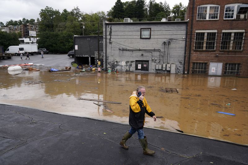 A man walks near a flooded area near the Swannanoa river, effects from Hurricane Helene , Friday, Sept. 27, 2024, in Asheville, N.C. (AP Photo/Erik Verduzco)