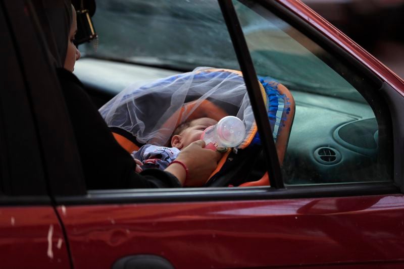 A woman feeds her newborn in a car in Sidon, Lebanon, as she flees the southern villages amid ongoing Israeli airstrikes, Monday, Sept. 23, 2024. (AP Photo/Mohammed Zaatari)