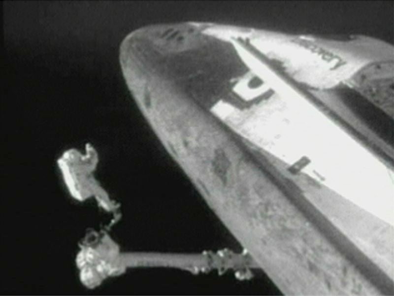 FILE - In this image from video provided by NASA, astronaut Steve Robinson maneuvers under the shuttle Discovery to remove gap fillers on Aug. 3, 2005, the first time in spacewalking history that an astronaut has ventured under the belly of a space shuttle and performed repairs. (NASA via AP, File)