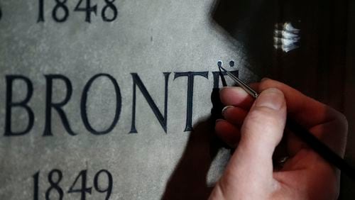 Conservator Lucy Ackland adds the finishing touches to the memorial to Charlotte, Emily and Anne Bronte at Poets' Corner in Westminster Abbey in London, England, Thursday Sept. 26, 2024. (Aaron Chown/PA via AP)