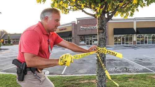 Clayton County police Lt. Thomas Reimers takes down crime-scene tape at the scene of a deadly shooting.