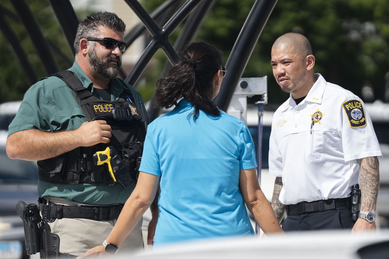 Forest Park Deputy Chief Christopher Chin, right, stands outside the Forest Park Blue Line train station in Forest Park, Ill., after giving a news conference about four people who were fatally shot on the train early Monday, Sept. 2, 2024. (Pat Nabong/Chicago Sun-Times via AP)