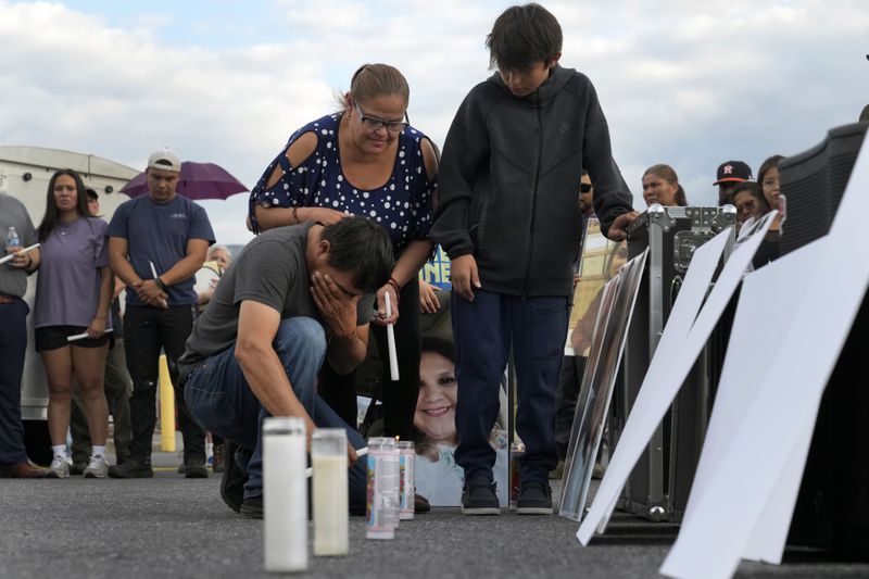 Daniel Delgado kneels in front of a photo of his wife, Monica Hernandez, who died at Impact Plastics during flooding caused by Hurricane Helene, while being comforted by his sister-in-law, Guadalupe Hernandez-Corona, during a vigil for victims of the tragedy in Erwin, Tenn., on Thursday, Oct. 3, 2024. (AP Photo/Jeff Roberson)