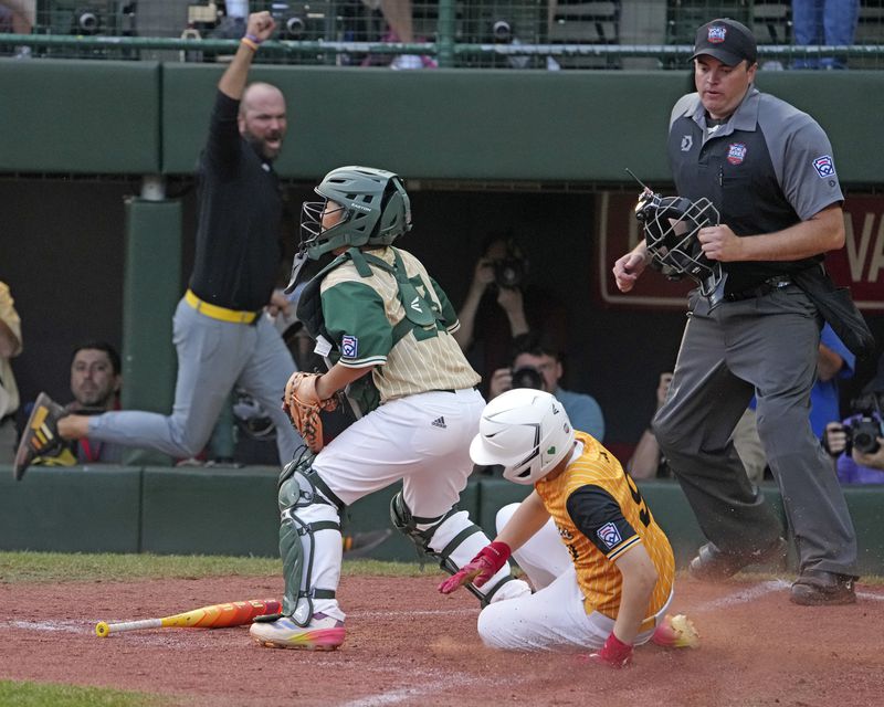 Lake Mary, Fla.'s Lathan Norton (9) scores behind Taiwan catcher Yu Chia-Jui for the walkoff winning run on a bunt by Hunter Alexander during the eighth inning of the Little League World Series Championship game in South Williamsport, Pa., Sunday, Aug. 25, 2024. (AP Photo/Gene J. Puskar)