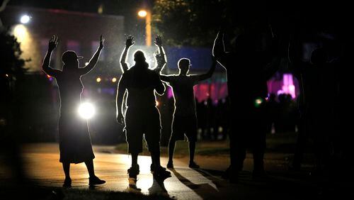 FILE - People raise their hands as police, trying to get them to disperse, move toward them during protests on Aug. 11, 2014 over the police shooting of Michael Brown in Ferguson, Mo. (AP Photo/Jeff Roberson, File)