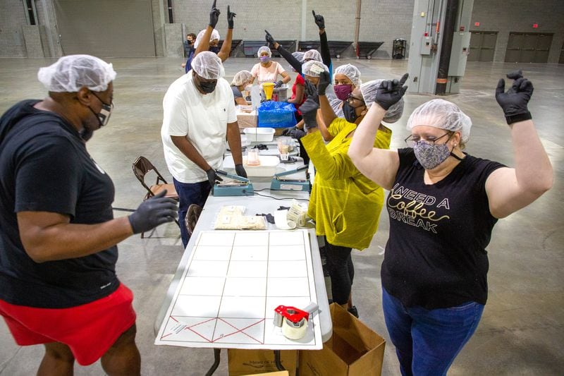 Tables celebrate each time they fill a box full of meals during the 9/11 National Day of Service at the Georgia World Congress Center on Sept. 11, 2021. During the event, hundreds of volunteers packed meals for the Atlanta Community Food Bank.  STEVE SCHAEFER FOR THE AJC