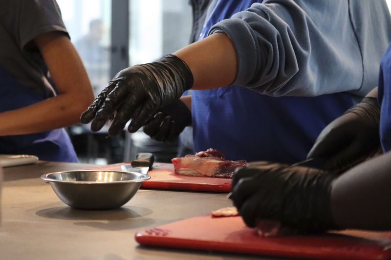 A George Westinghouse Career and Technical Education High School student participates in a butchery class at Essex Kitchen in New York, Tuesday, May 21, 2024. (AP Photo/James Pollard)