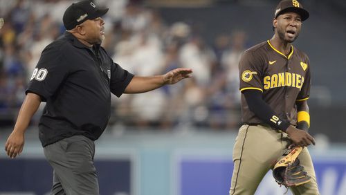 San Diego Padres left fielder Jurickson Profar, right, talks to umpire Adrian Johnson after items were thrown at Profar in the outfield during the seventh inning in Game 2 of a baseball NL Division Series against the Los Angeles Dodgers, Sunday, Oct. 6, 2024, in Los Angeles. (AP Photo/Ashley Landis)