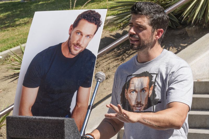 Micah Parker, "Vampire Diaries," actor, producer, and organizer of Justice for Johnny Wactor, speaks during a news conference outside Los Angeles City Hall in Los Angeles Tuesday, Aug. 13, 2024, asking citizens to help find the suspects that murdered the former "General Hospital" actor seen in pictures. (AP Photo/Damian Dovarganes)