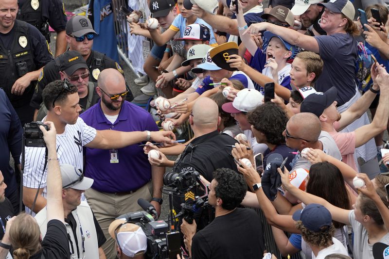 New York Yankees' Aaron Judge, left center, gives autographs to fans as the New York Yankees arrive at the Little League World Series Complex to watch the Little League World Series tournament in South Williamsport, Pa., Sunday, Aug. 18, 2024. (AP Photo/Tom E. Puskar)