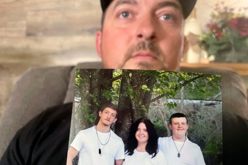 Ryan Craddock holds a photo of his three children, from left Shawn Craddock, 18; Kendall Craddock, 17, and Cohen Craddock, 13, at his home in Hewett, W. Va., on Thursday, Aug. 29, 2024. Cohen died Saturday, Aug. 24, 2024, a day after he received a head injury while making a tackle during his middle school's football practice. (AP Photo/John Raby)