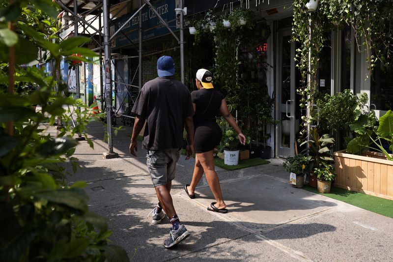 People walk past stores in the Harlem neighborhood of New York, Thursday, Aug. 15, 2024. (AP Photo/Pamela Smith)