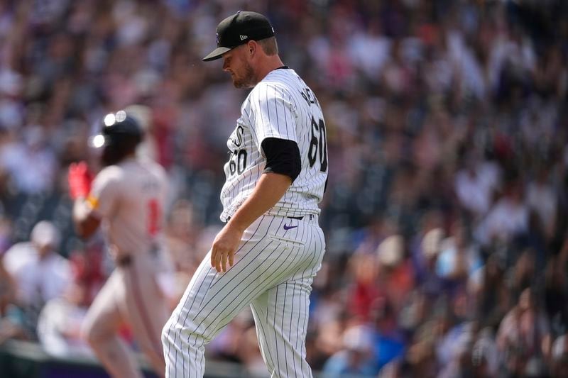 Colorado Rockies relief pitcher Josh Rogers, front, reacts after giving up a solo home run to Atlanta Braves' Jorge Soler, back, in the eighth inning of a baseball game Sunday, Aug. 11, 2024, in Denver. (AP Photo/David Zalubowski)