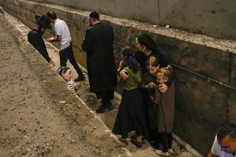 People take cover on the side of the road as a siren sounds a warning of incoming missiles on a freeway in Shoresh, Israel Tuesday, Oct. 1, 2024. (AP Photo/Ohad Zwigenberg)