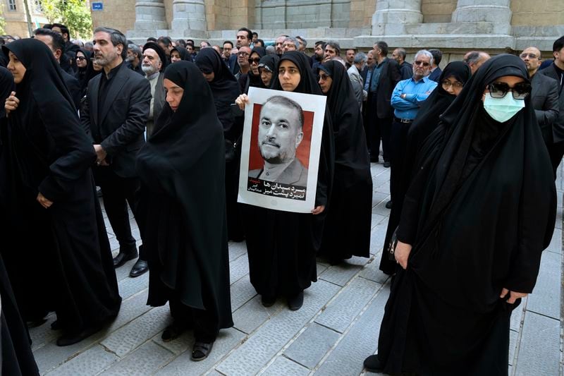 A woman holds a poster of the late Iranian Foreign Minister Hossein Amirabdollahian, who was killed in a helicopter crash along with President Ebrahim Raisi, during his funeral ceremony at the foreign ministry in Tehran, Iran, Thursday, May 23, 2024. The death of Raisi, Amirabdollahian and six others in the crash on Sunday comes at a politically sensitive moment for Iran, both at home and abroad. (AP Photo/Vahid Salemi)