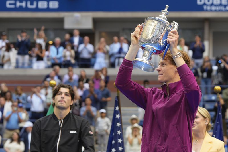 Jannik Sinner, of Italy, holds the championship trophy as Taylor Fritz, of the United States, looks on after sinner won the men's singles final of the U.S. Open tennis championships, Sunday, Sept. 8, 2024, in New York. (AP Photo/Kirsty Wigglesworth)