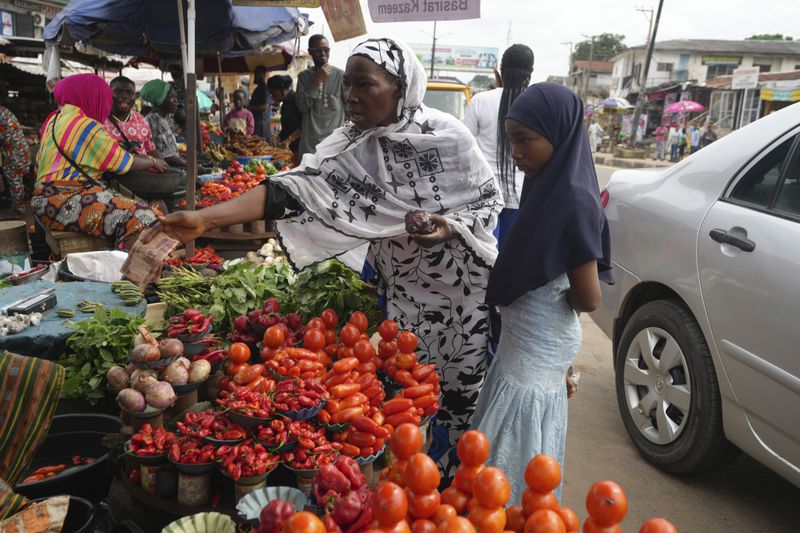 Idowu Bello, 56, buys onions to prepare a pot of soup at a market in Ibadan, Nigeria, Friday, Sept. 13, 2024. (AP Photo/Sunday Alamba)