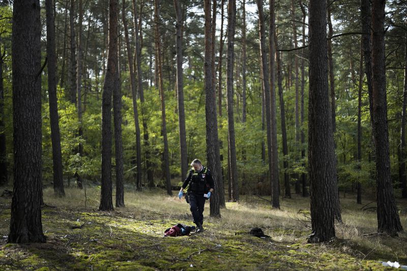 FILE - Federal Police officer Frank Malack looks at the belongings of migrants who illegally crossed the border from Poland into Germany during a patrol in a forest near Forst, southeast of Berlin, Germany, Oct. 11, 2023. (AP Photo/Markus Schreiber, File)