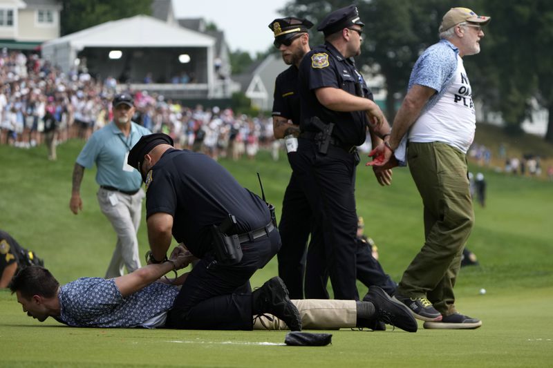 Protesters are taken into custody after they ran onto the course on the 18th hole during the final round of the Travelers Championship golf tournament at TPC River Highlands, Sunday, June 23, 2024, in Cromwell, Conn. (AP Photo/Seth Wenig)