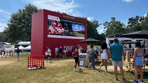 Some fans at East Lake Golf Club gather around a large screen that showed the Georgia-Clemson college football game during the third round of the Tour Championship.