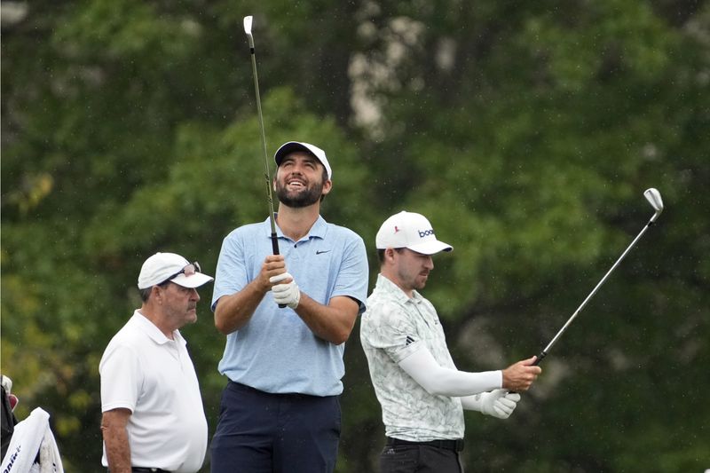 Scottie Scheffler, center, and Nick Taylor, right, of Canada, work on the driving range at the St. Jude Championship golf tournament Wednesday, Aug. 14, 2024, in Memphis, Tenn. The tournament is scheduled to begin Thursday. (AP Photo/Mark Humphrey)