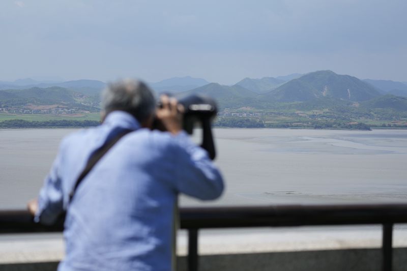 A visitor uses binoculars to see the North Korean side from the unification observatory in Paju, South Korea, Tuesday, June 25, 2024. South Korea threatened Tuesday to restart anti-Pyongyang frontline propaganda broadcasts in the latest bout of Cold War-style campaigns between the rivals after North Korea resumed its trash-carrying balloon launches. (AP Photo/Lee Jin-man)