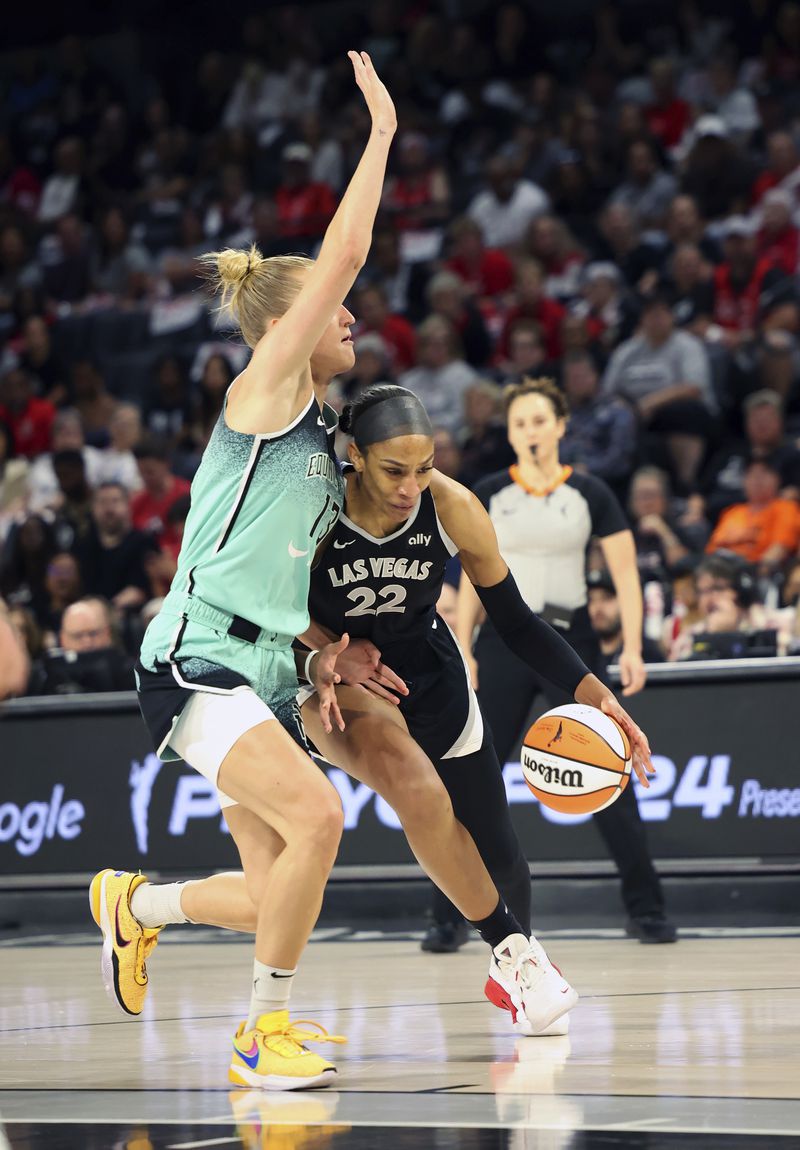 Las Vegas Aces center A'ja Wilson (22) drives the ball around New York Liberty forward Leonie Fiebich (13) during a WNBA basketball semifinal game Friday, Oct. 4, 2024, in Las Vegas. (AP Photo/Ronda Churchill)