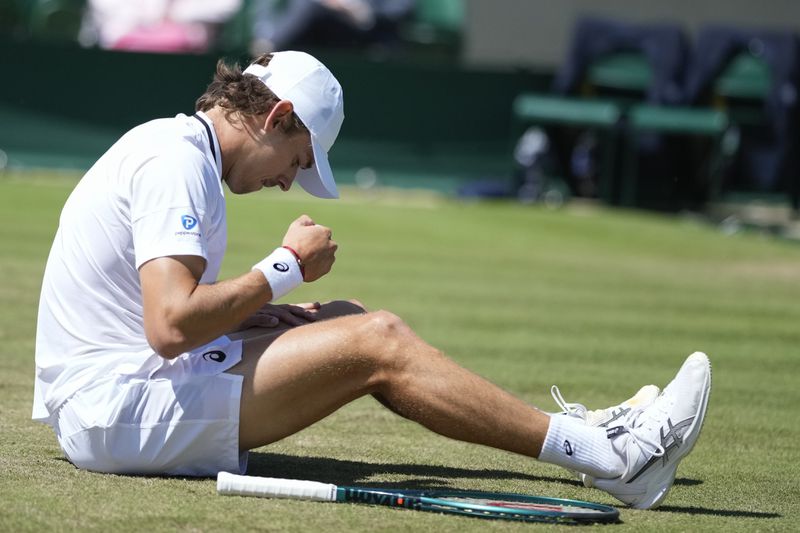 Alex de Minaur of Australia sits on the grass after a fall during his second round match against Jaume Munar of Spain at the Wimbledon tennis championships in London, Thursday, July 4, 2024. (AP Photo/Mosa'ab Elshamy)