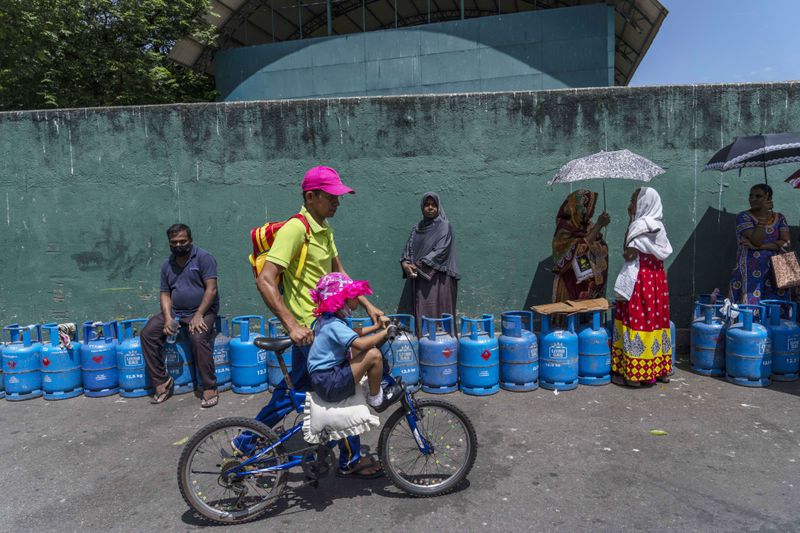 FILE - People wait in a queue with empty cylinders to buy domestic gas at a distribution center, in Colombo, Sri Lanka, on July 12, 2022. (AP Photo/Rafiq Maqbool, File)