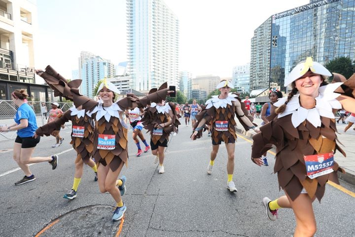 Costumed runners celebrate at the start of the 55th running of the Atlanta Journal-Constitution Peachtree Road Race in Atlanta on Thursday, July 4, 2024.   (Miguel Martinez / AJC)