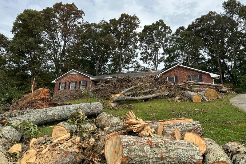 Cut up sections of a tree sit on front of a house Friday, Oct. 4, 2024, in the Oak Forest neighborhood of Asheville, N.C., in the aftermath of Hurricane Helene. (AP Photo/Jeff Amy)