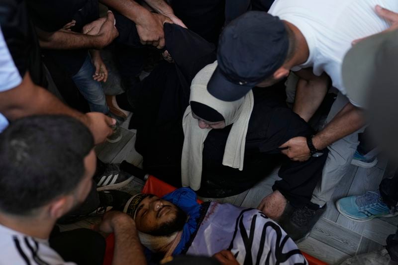 Mourners take the last look at the body of Yazeed Shafea, 22, wrapped with an Islamic Jihad flag, who was one of four Palestinians killed by an Israeli airstrike late Tuesday, during their funeral in the West Bank refugee camp of Nur Shams, near Tulkarem, Wednesday, July 3, 2024. Palestinian health officials say four Palestinians were killed by an Israeli airstrike in a refugee camp in the northern West Bank late Tuesday. Israel's military said an aircraft struck a group of militants who were planting explosives in Nur Shams refugee camp near Tulkarem. (AP Photo/Nasser Nasser)
