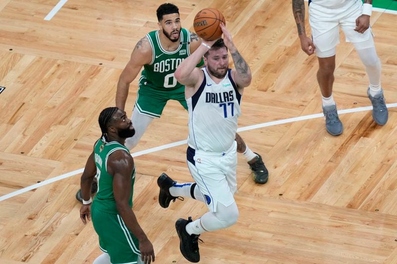 Dallas Mavericks guard Luka Doncic (77)goes up to shoot at the basket in front of Boston Celtics guard Jaylen Brown, left, and forward Jayson Tatum (0) during the first half of Game 5 of the NBA basketball finals, Monday, June 17, 2024, in Boston. (AP Photo/Michael Dwyer)