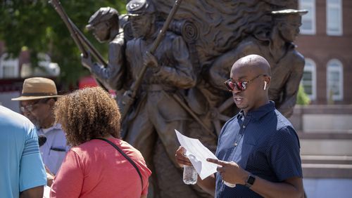 Associated Press reporter Darren Sands, right, reads the names of United States Colored Troops regimental soldiers, including his great-great-great-great grandfather Hewlett Sands, at the African American Civil War Memorial as part of Juneteenth commemorations on Wednesday, June 19, 2024, in Washington. (AP Photo/Mark Schiefelbein)