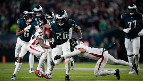 Philadelphia Eagles running back Saquon Barkley (26) runs with the ball under pressure from Atlanta Falcons cornerback A.J. Terrell (24) and Atlanta Falcons safety Jessie Bates III during the second half of an NFL football game on Monday, Sept. 16, 2024, in Philadelphia. (AP Photo/Matt Slocum)