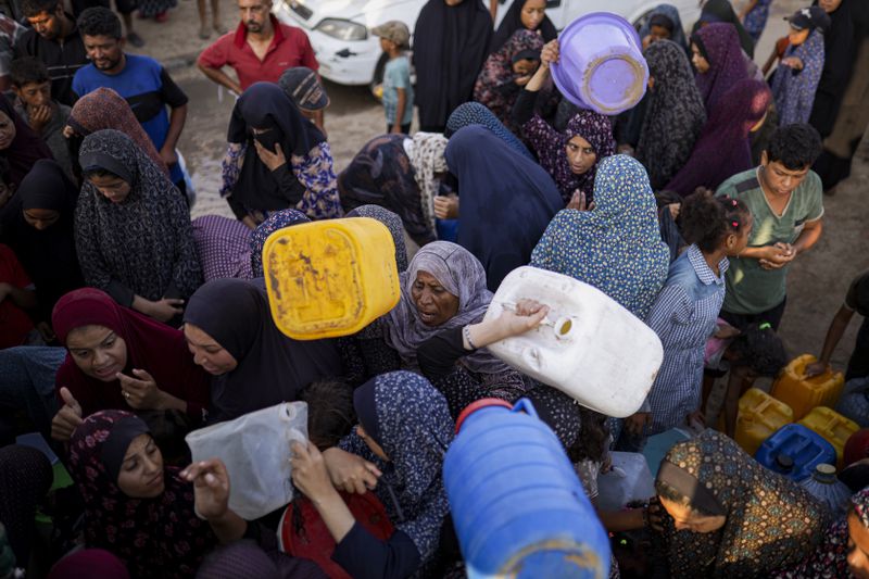Palestinians displaced by the Israeli bombardment of the Gaza Strip queue for water at a makeshift tent camp in the southern town of Khan Younis, Monday, July 1, 2024. (AP Photo/Jehad Alshrafi)