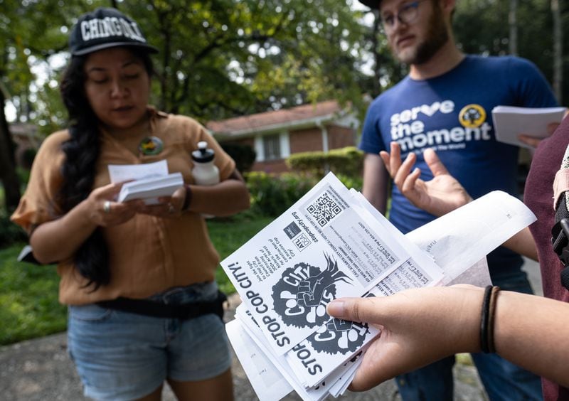 Eva Cardenas (left) Seth Roseman and Shehza Anjum huddle while canvasing neighborhoods in opposition of the proposed police and fire training center.  Ben Gray for the Atlanta Journal-Constitution