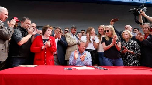 Gov. Brian Kemp signs a bill, which will allow permitless carry, at a gun store In Douglasville on Tuesday, April 12, 2022. SB 319 allows a “lawful weapons carrier” to carry a concealed handgun everywhere license holders currently are allowed. (Bob Andres / robert.andres@ajc.com)