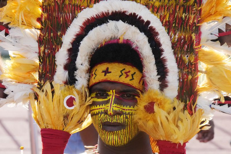 A man wears face paint a a traditional headdress as he waits for Pope Francis to give an address during meeting with young people in the Sir John Guise Stadium in Port Moresby, Papua New Guinea, Monday, Sept. 9, 2024. (AP Photo/Mark Baker)