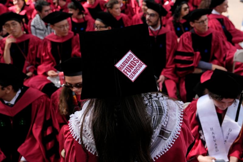 Phoebe Carter, who will graduate from the Graduate School of Arts and Sciences later in the day, watches as students march to their seats in Harvard Yard during commencement at Harvard University, Thursday, May 23, 2024, in Cambridge, Mass. (AP Photo/Charles Krupa)